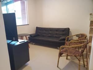 sala de estar con sofá negro y sillas en Village de Praia Duplex Arembepe, en Camaçari