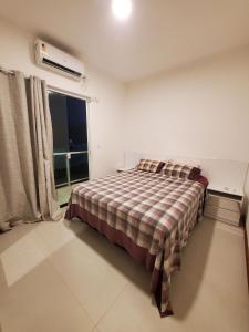 1 dormitorio con 1 cama con manta a cuadros y ventana en Village de Praia Duplex Arembepe, en Camaçari