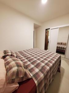 1 dormitorio con 1 cama con manta a cuadros en Village de Praia Duplex Arembepe, en Camaçari