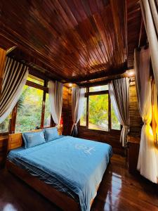 a bedroom with a bed in a room with windows at Mountain House Phú Quốc in Phu Quoc
