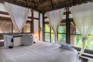 a bedroom with a large white bed with windows at Villa Santuario Lake front Oasis in Bacalar