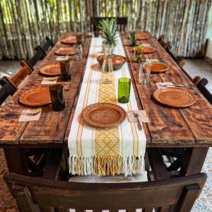 una larga mesa de madera con platos y platos. en Villa Santuario Lake front Oasis en Bacalar