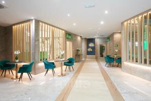 a waiting room with green chairs and tables at Allure Healthy Hotel & Spa in Eger