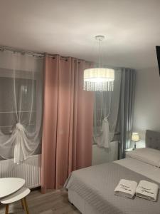 1 dormitorio con cortinas rosas, 1 cama y lámpara de araña en Parkowy Kudowa en Kudowa-Zdrój