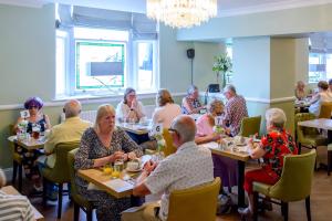 un grupo de personas sentadas en mesas en un restaurante en County Hotel, en Kendal