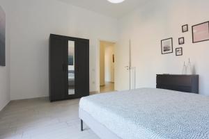 een witte slaapkamer met een bed en een zwarte deur bij Bright & Central Apartment near the station in Salerno