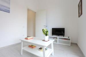 een witte woonkamer met een witte tafel en een tv bij Bright & Central Apartment near the station in Salerno