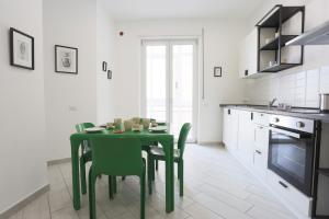 een keuken met een groene tafel en stoelen bij Bright & Central Apartment near the station in Salerno