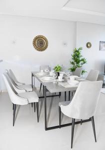 a white dining room with a white table and chairs at Live close to Lagoons Canal - 1 BR Apartment in Ras al Khaimah
