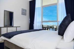 a bedroom with a large white bed with a window at Live close to Lagoons Canal - 1 BR Apartment in Ras al Khaimah