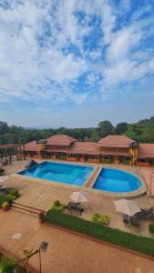 a large swimming pool with umbrellas in front of a building at MAP RESORT in Alibaug