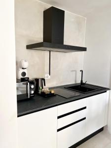 uma cozinha com armários brancos e um balcão preto em Artemide Luxury Home em Siracusa