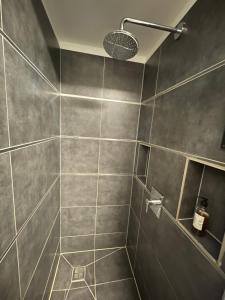 a bathroom with a gray tiled shower with a light at TruRetreats Design Loft I Riesige Küche I Wallbox I 65z SmartTV I 150qm in Hamburg