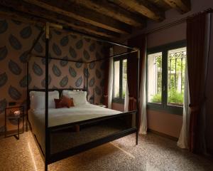 a bedroom with a four poster bed and windows at Madama Garden Retreat in Venice
