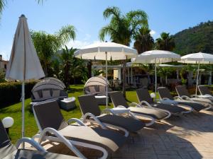 eine Reihe von Liegestühlen und Sonnenschirmen in der Unterkunft Sentido Michelizia Tropea Resort in Tropea