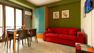 een woonkamer met een rode bank en een tafel bij Appartamento Carmi con giardino in Siracusa