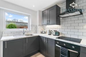 a kitchen with gray cabinets and a sink and a window at Grangemouth, 3 Bed House, Free Parking, Business or Leisure in Grangemouth
