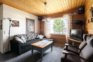 een woonkamer met een bank en een tv bij Sinikallio | Paajoen Vuokramökit in Himos