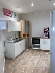uma cozinha com armários brancos e piso em azulejo em Gîte Amazonia em Dijon