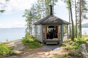 una pequeña casa al lado de un cuerpo de agua en Sinikallio | Paajoen Vuokramökit, en Himos