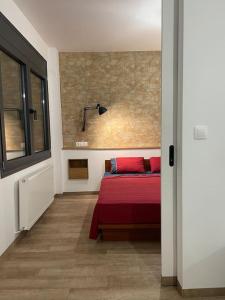 a bedroom with a bed with red sheets and a window at Central cozy apartment with garden in Alexandroupoli
