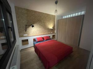 Schlafzimmer mit einem Bett mit roter Bettwäsche und einem TV in der Unterkunft Central cozy apartment with garden in Alexandroupoli
