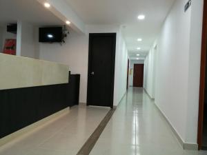 un pasillo vacío con una puerta negra y un televisor en Hotel Don Jose en Ciénaga