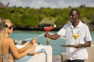 un hombre y una mujer sosteniendo bebidas en una mesa en Blue Moon Resort, en Jambiani