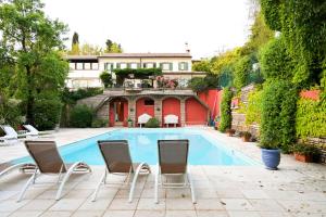 a swimming pool with chairs and a house at Villa Isidoro ampio parco piscina privata in Verona