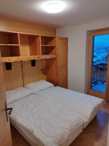 - une chambre avec un lit doté d'une tête de lit en bois et d'une fenêtre dans l'établissement Pracondu OUTDOOR & FUN appartement 2 chambres avec Balcon, à Nendaz