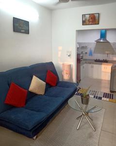 een blauwe bank in een woonkamer met een tafel bij House 44 1BHK in Greater Noida