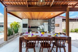 an open kitchen and dining room with a wooden table and chairs at Incrível casa na Praia de Camurupim por Carpediem in Nísia Floresta