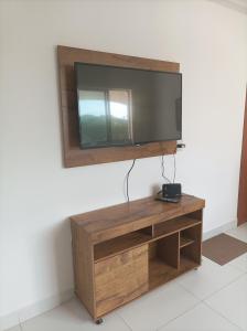 TV de pantalla plana en la parte superior de un centro de entretenimiento de madera en Seu apartamento em Ilhéus, en Ilhéus