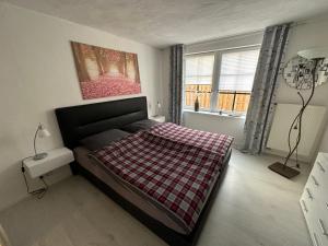 a bedroom with a bed with a checkered blanket on it at Huus an`t Koornfeld, Urlaub an der Nordsee im Herzen von Ostfriesland, Nahe Norden-Norddeich in Osteel