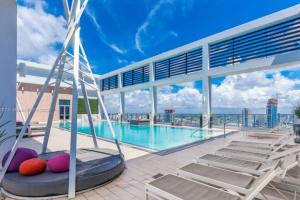 a swimming pool with lounge chairs and a large building at Sun-Splashed 1BR Condo unit in DWTN Miami with WFH in Miami