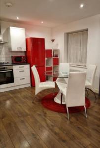 a kitchen with a glass table and white chairs at Chi's apartment in Barking
