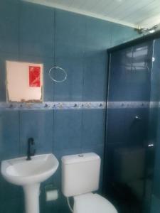 a blue bathroom with a toilet and a sink at Pousada Chalé Boracéia in Boracéia