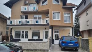 een huis met een blauwe auto die ervoor geparkeerd staat bij Apartman San in Brčko