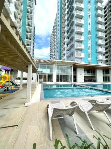 a swimming pool with two chairs and some buildings at One bedroom Condo Suite in Bacolod City in Bacolod