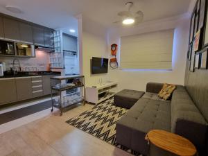 a living room with a couch and a kitchen at Novíssimo Apto no CENTRO de Aguas de Sao Pedro in Águas de São Pedro