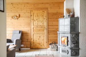 een open haard in een woonkamer met een houten muur bij Kujanpää | Paajoen Vuokramökit in Himos