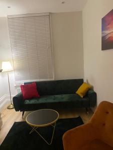 a living room with a green couch with colorful pillows at I&J Suites in Woolwich