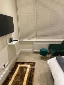 a bedroom with a bed and a green chair and a rug at I&J Suites in Woolwich