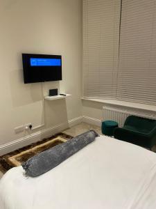 a bedroom with a bed and a flat screen tv at I&J Suites in Woolwich