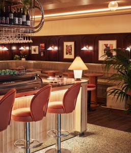 a bar in a restaurant with red stools at The Hoxton, Shepherds Bush in London