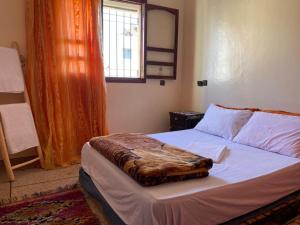 um quarto com uma cama com um cobertor em Emallayan Hostel em Imsouane