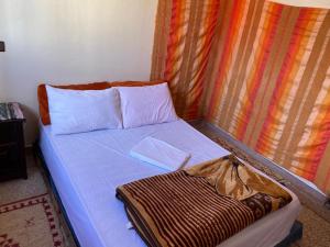 uma cama num quarto com em Emallayan Hostel em Imsouane