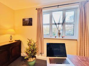 a laptop sitting on a desk in a room with a window at Dapps Hill Haven - between Bristol and Bath, both 9 mins by train! in Keynsham