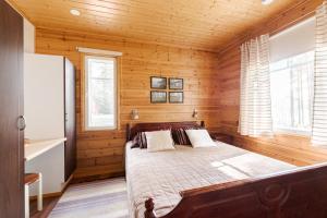 1 dormitorio con 1 cama en una habitación de madera en Suvituuli | Paajoen Vuokramökit en Himos
