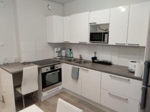 kuchnia z białymi szafkami, zlewem i kuchenką mikrofalową w obiekcie M Apartments Rahola w mieście Tampere
